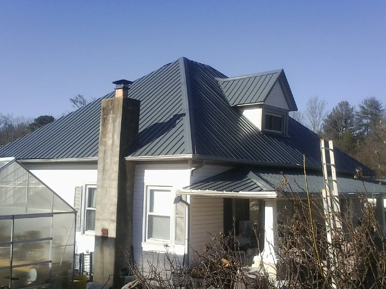 Dark blue standing seam metal roof on a white farmhouse with dormer — Slate & Tile Roof Repair by Roofing Brothers in Palo