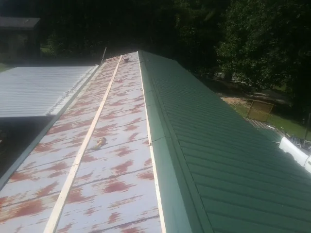 Old rusted panels beside newly installed green metal roofing — Wind Damage Roof Repair by Roofing Brothers in Palo