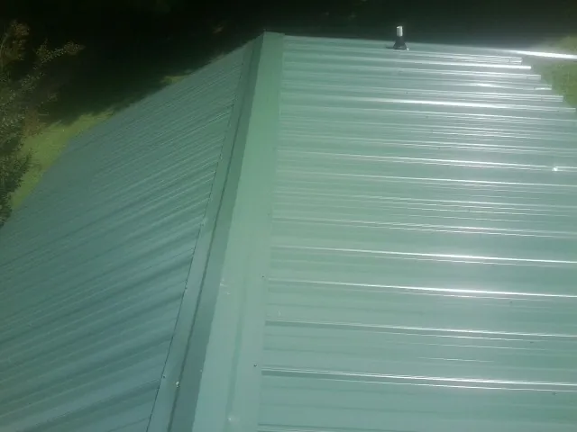 New green metal panels meeting at the ridge of a roof — Flat Roof Repair work by our crew in Palo