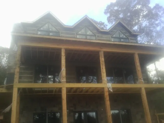 Dormers and porch framing on a large log home under construction — Roof Coating work by our crew in Palo
