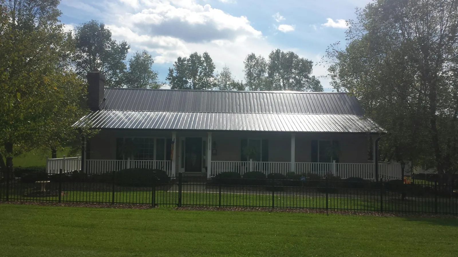 Gray metal roof on a brick ranch with a full width front porch — Gutter Guard Installation work by our crew in Palo