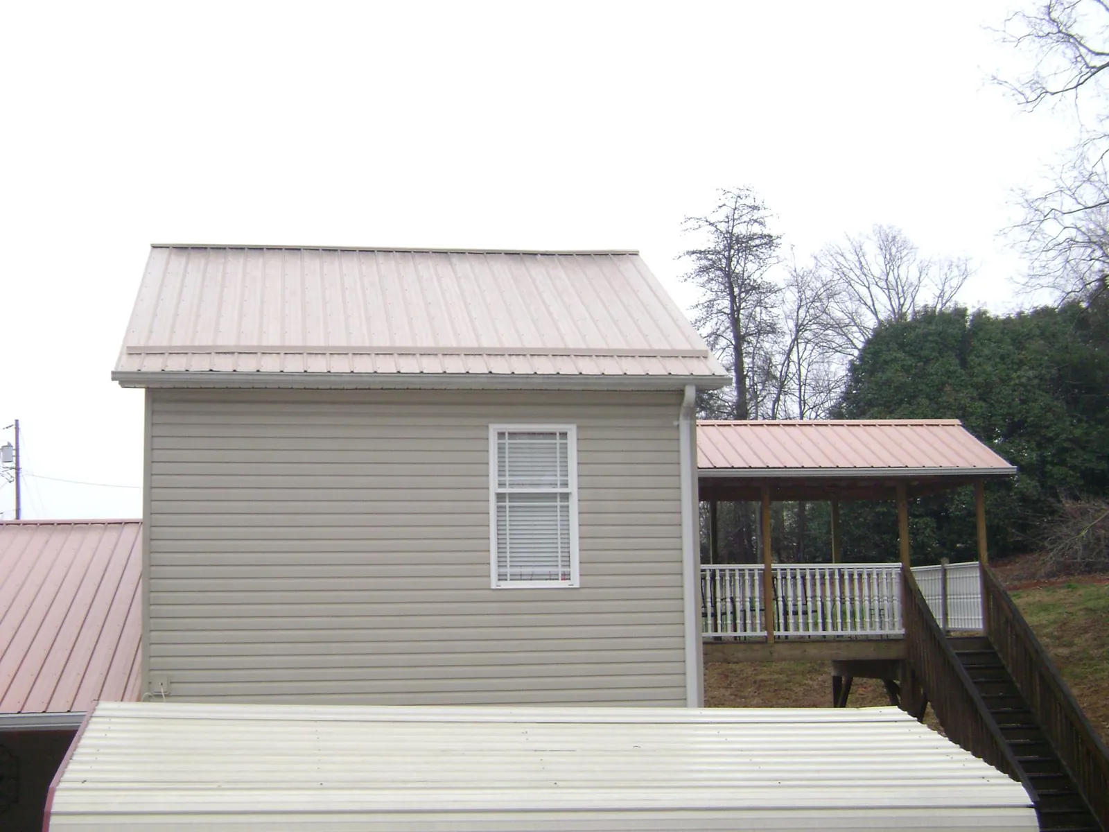 Tan metal roofs on a two story addition and attached porch, from a Roof Replacement job in Palo