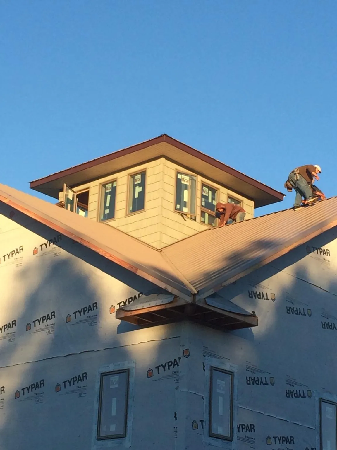 Roofers working around a rooftop cupola on a new metal roof at sunset — Roof Waterproofing in Palo by Roofing Brothers